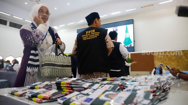 Petugas membagikan paspor calon jamaah haji di Asrama Haji Pondok Gede, Jakarta, Senin (5/5/2025). [Suara.com/Alfian Winanto]
