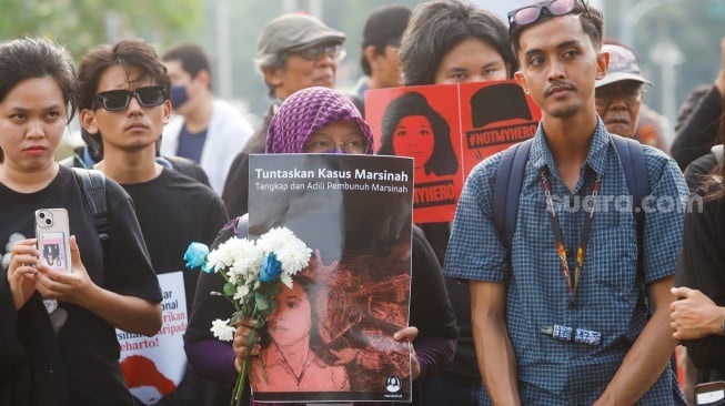 Aktivis Jaringan Solidaritas Korban untuk Keadilan membawa poster Marsinah saat mengikuti aksi Kamisan ke-860 di depan Istana Merdeka, Jakarta, Kamis (8/5/2025). [Suara.com/Alfian Winanto]