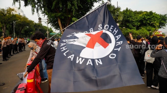 Aktivis Jaringan Solidaritas Korban untuk Keadilan membawa bendera bergambar Soeharto saat mengikuti aksi Kamisan ke-860 di depan Istana Merdeka, Jakarta, Kamis (8/5/2025). [Suara.com/Alfian Winanto]