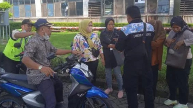 Petugas keamanan PT Nikomas Gemilang mengamankan seorang perempuan (tengah) yang menjadi calo tenaga kerja. [Istimewa]