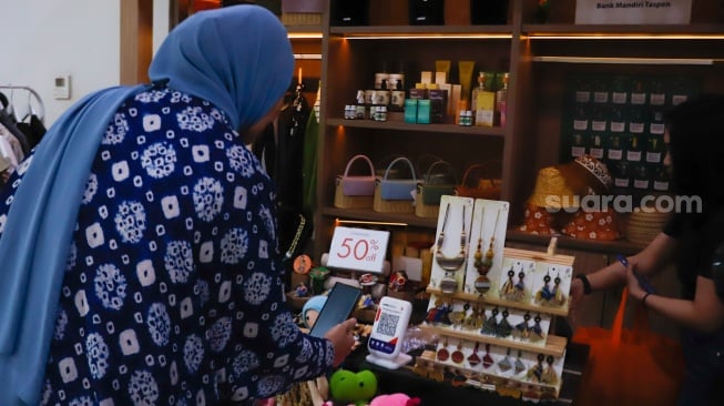 Pembeli memindai Kode Respons Cepat Standar (QRIS) di Sarinah, Jakarta, Selasa (13/5/2025). [Suara.com/Alfian Winanto]