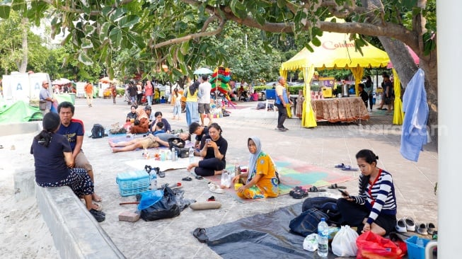 Pengunjung berwisata di Pantai Lagoon, Taman Impian Jaya Ancol, Jakarta, Selasa (13/5/2025). [Suara.com/Alfian Winanto]