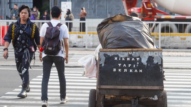 Pekerja berjalan sepulang bekerja di kawasan Jalan MH Thamrin, Jakarta, Rabu (14/5/2025). [Suara.com/Alfian Winanto]