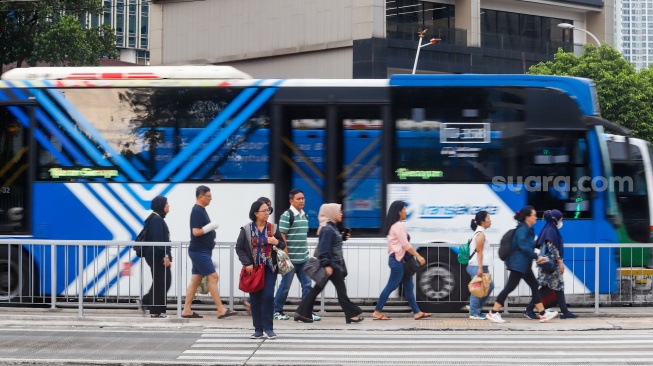 Pekerja berjalan sepulang bekerja di kawasan Jalan MH Thamrin, Jakarta, Rabu (14/5/2025). [Suara.com/Alfian Winanto]