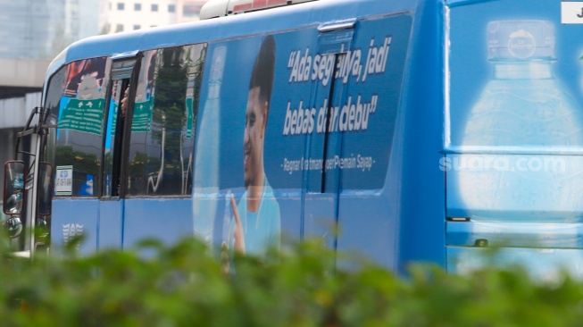 Pekerja menaiki bus Transjakarta di kawasan Jalan MH Thamrin, Jakarta, Rabu (14/5/2025). [Suara.com/Alfian Winanto]