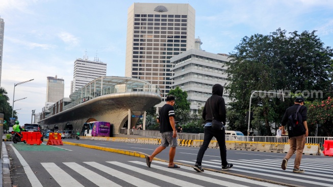 Pekerja berjalan sepulang bekerja di kawasan Jalan MH Thamrin, Jakarta, Rabu (14/5/2025). [Suara.com/Alfian Winanto]