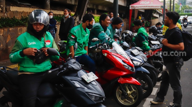 Pengemudi ojek daring menunggu penumpang di Stasiun Sudirman, Jakarta, Senin (20/5/2025). [Suara.com/Alfian Winanto]
