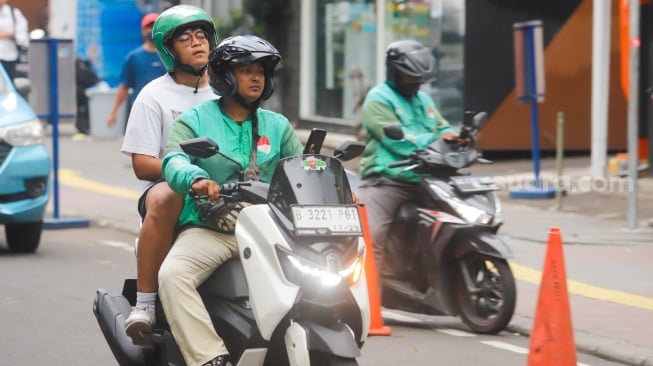 Pengemudi ojek daring mengantar penumpang di Stasiun Sudirman, Jakarta, Senin (20/5/2025). [Suara.com/Alfian Winanto]