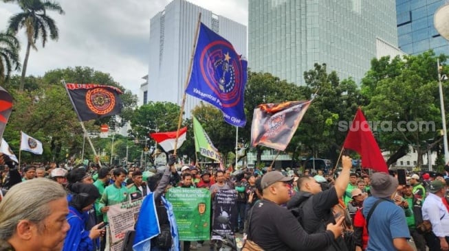 Penampakan sejumlah elemen komunitas ojek online (ojol) menggelar aksi unjuk rasa di depan Patung Kuda Arjuna Wijaya, Gambir, Jakarta Pusat (Jakarta Pusat) pada Selasa (20/5/2025). (Suara.com/Fakhri Fuadi)