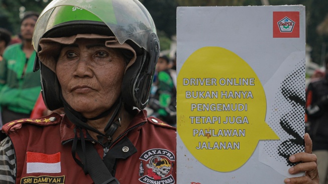 Seorang pengemudi ojek daring membawa poster tuntutan saat unjuk rasa di kawasan Patung Kuda, Jakarta, Selasa (20/5/2025). [ANTARA FOTO/Jasmine Nadhya Thanaya/rwa]