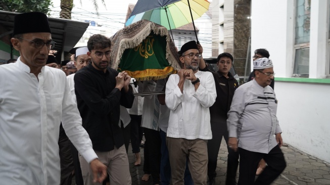 Anak Najwa Shihab, Izzat Ibrahim Assegaf (baju hitam) saat menandu keranda jenazah sang ayah, Ibrahim Sjarief Assegaf di TPU Jeruk Purut, Jakarta, Rabu, 21 Mei 2025. [dok: Narasi]
