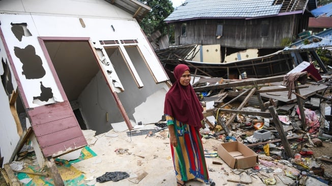 Warga berdiri di depan rumahnya yang rusak akibat tanah amblas di kawasan jalan Poros Samarinda-Balikpapan di Desa Batuah, Loa Janan, Kabupaten Kutai Kartanegara, Kalimantan Timur, Minggu (25/5/2025). [ANTARA FOTO/M Risyal Hidayat/YU]