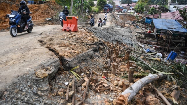 Pengendara sepeda motor melintasi jalan yang amblas di jalan Poros Samarinda-Balikpapan di Desa Batuah, Loa Janan, Kabupaten Kutai Kartanegara, Kalimantan Timur, Minggu (25/5/2025). [ANTARA FOTO/M Risyal Hidayat/YU]