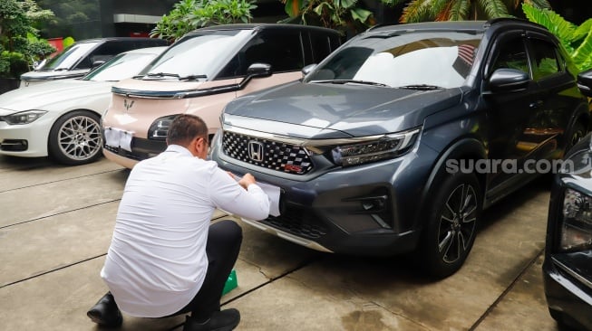 Petugas memeriksa kendaraan yang menjadi barang sitaan di Gedung Merah Putih Komisi Pemberantasan Korupsi (KPK), Jakarta, Senin (26/5/2025). [Suara.com/Alfian Winanto] 