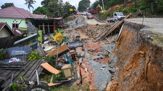 Pengendara mobil melintasi jalan yang amblas di jalan Poros Samarinda-Balikpapan di Desa Batuah, Loa Janan, Kabupaten Kutai Kartanegara, Kalimantan Timur, Minggu (25/5/2025). [ANTARA FOTO/M Risyal Hidayat/YU]