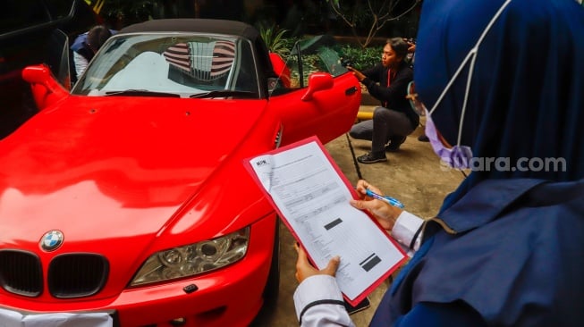 Petugas memeriksa kendaraan yang menjadi barang sitaan di Gedung Merah Putih Komisi Pemberantasan Korupsi (KPK), Jakarta, Senin (26/5/2025). [Suara.com/Alfian Winanto] 