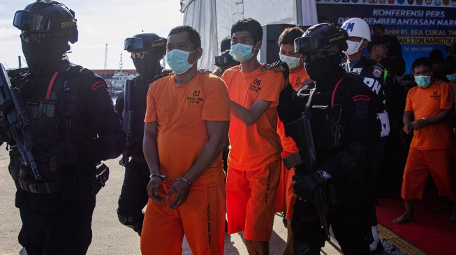 Personel Brimob menggiring tersangka kasus penyelupan sabu-sabu saat pengungkapan kasus di Pelabuhan Bea Cukai Batam, Kepulauan Riau, Senin (26/5/2025). [ANTARA FOTO/Teguh Prihatna/Spt]