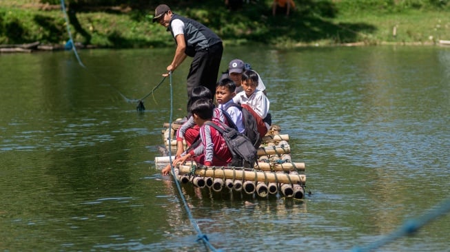 Sejumlah siswa SDN Panaruban menyeberangi sungai Cicadas menggunakan rakit di Desa Karanganyar, Cililin, Kabupaten Bandung Barat, Jawa Barat, Selasa (27/5/2025). [ANTARA FOTO/Abdan Syakura/Spt]