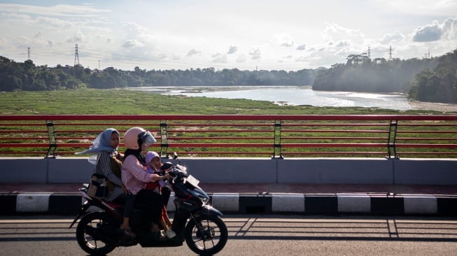 Pengendara melintasi jembatan di atas aliran sungai Citarum yang dipenuhi sampah dan eceng gondok di Batujajar, Kabupaten Bandung Barat, Jawa Barat, Selasa (27/5/2025). [ANTARA FOTO/Abdan Syakura/bar]