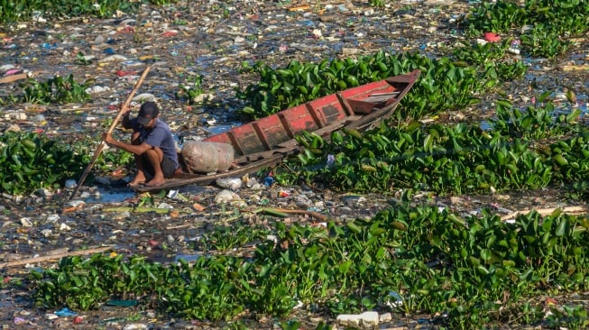Warga menggunakan perahu melintas di aliran sungai Citarum yang dipenuhi sampah dan eceng gondok di Batujajar, Kabupaten Bandung Barat, Jawa Barat, Selasa (27/5/2025). [ANTARA FOTO/Abdan Syakura/bar]