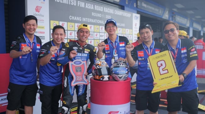 Pembalap Yamaha Racing Indonesia Candra Hermawan (ketiga dari kiri) memamerkan piala yang diraih setelah berhasil merebut podium kedua di kelas AP250 ajang ARRC 2025 putaran pertama di Buriram, Thailand pada April 2025. Ia berambisi mengulang prestasi tersebut di putaran kedua yang akan digelar di Sepang, Malaysia pada 1 Juni 2025. [Dok PT YIMM]