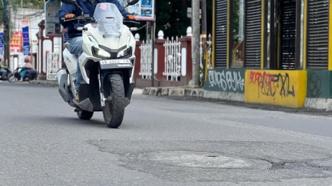 Ilustrasi pengendara motor saat melintas di jalan berlubang (Dok Asmo)