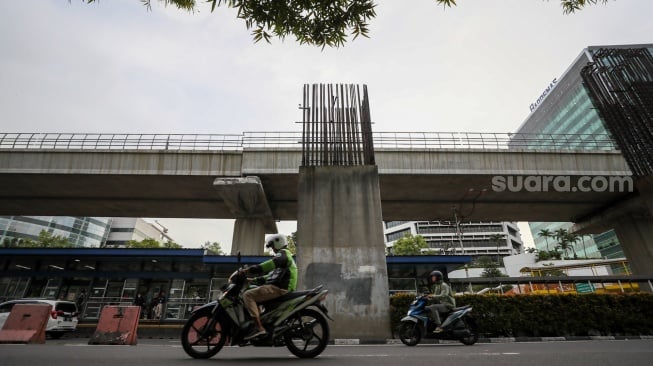 Pengendara melintas di dekat tiang bekas proyek monorel Jakarta di kawasan Jalan HR Rasuna Said, Jakarta, Senin (2/6/2025). [Suara.com/Alfian Winanto]