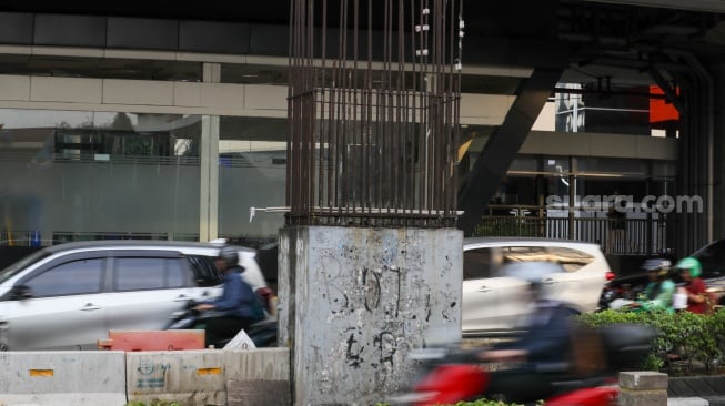 Pengendara melintas di dekat tiang bekas proyek monorel Jakarta di kawasan Jalan HR Rasuna Said, Jakarta, Senin (2/6/2025). [Suara.com/Alfian Winanto]