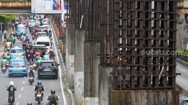 Pengendara melintas di dekat tiang bekas proyek monorel Jakarta di kawasan Jalan HR Rasuna Said, Jakarta, Senin (2/6/2025). [Suara.com/Alfian Winanto]