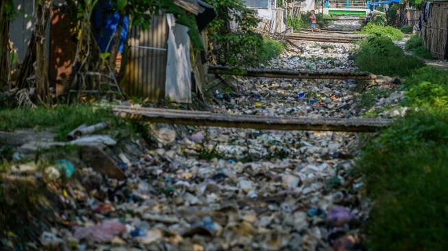 Seorang anak berjalan diatas di saluran irigasi yang dipenuhi sampah di Desa Susukan, Kabupaten Serang, Banten, Senin (2/6/2025). [ANTARA FOTO/Muhammad Bagus Khoirunas/bar]