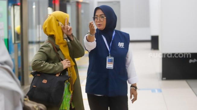 Pekerja lanjut usia (lansia) menyapa pengguna MRT Jakarta di Stasiun Bundaran HI, Jakarta, Selasa (3/6/2025). [Suara.com/Alfian Winanto]