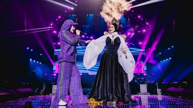 Melly Goeslaw menggandeng Aina Abdul saat menggelar konser di Malaysia pada 31 Mei 2025. [Instagram]