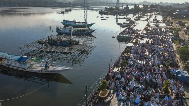 Foto udara umat Islam melaksanakan shalat Idul Adha 1446 H dengan latar belakang Jembatan Teluk Kendari di RTH Papalimpa Puday, Kendari, Sulawesi Tenggara, Jumat (6/6/2025). [ANTARA FOTO/Andry Denisah/nym]