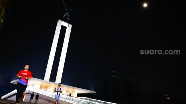 Warga beraktivitas saat malam hari di Taman Lapangan Banteng, Jakarta, Senin (9/6/2025). [Suara.com/Alfian Winanto]