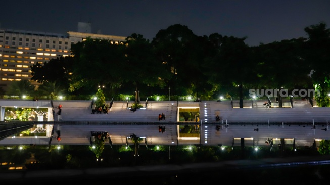 Warga beraktivitas saat malam hari di Taman Lapangan Banteng, Jakarta, Senin (9/6/2025). [Suara.com/Alfian Winanto]