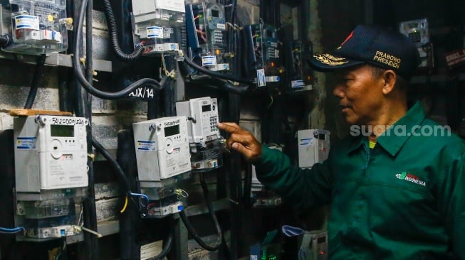 Petugas mengecek meteran listrik di Rusun Bendungan Hilir, Jakarta, Selasa (10/6/2025). [Suara.com/Alfian Winanto]