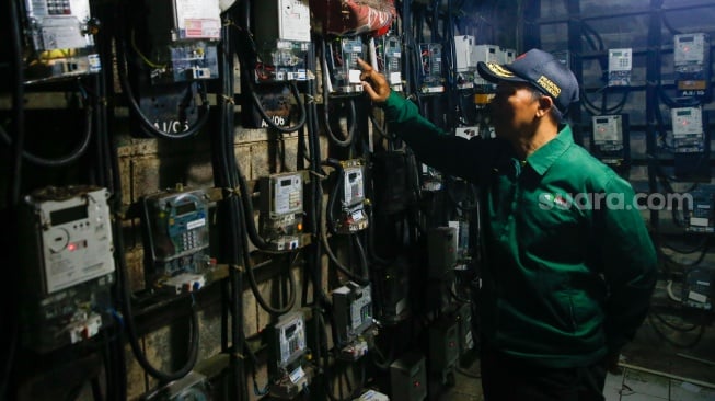 Petugas mengecek meteran listrik di Rusun Bendungan Hilir, Jakarta, Selasa (10/6/2025). [Suara.com/Alfian Winanto]