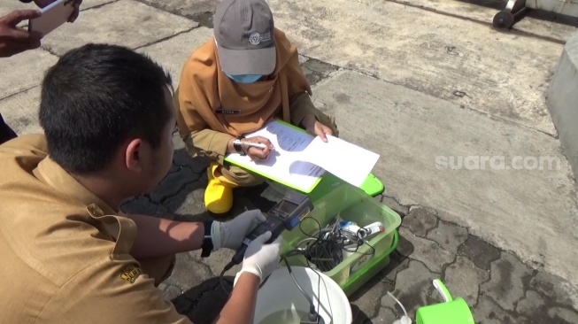 Petugas dari Dinas Lingkungan Hidup melakukan pengecekan air di tambak di Desa Sayung, Kecamatan Sayung, Kabupaten Demak, Selasa (10/6/2025). (suara.com/Sigit AF)