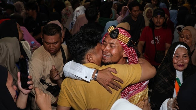Jamaah haji memeluk kerabatnya saat tiba di Asrama Haji Makassar, Sulawesi Selatan, Kamis (12/6/2025) dini hari. [ANTARA FOTO/Arnas Padda/bar]