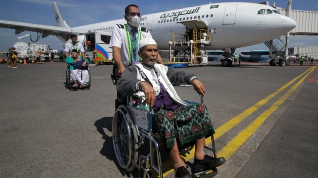 Petugas mendorong kursi roda jamaah haji kelompok terbang (kloter) pertama saat tiba di Bandara Internasional Juanda Surabaya di Sidoarjo, Jawa Timur, Kamis (12/6/2025). [ANTARA FOTO/Umarul Faruq/bar]