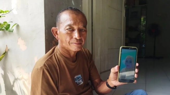 Suami ibu rumah tangga (IRT) yang diduga jadi korban pembunuhan menujukan foto korban. [IST/Maulana BantenNews]