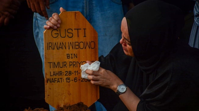Anggota keluarga membersihkan nisan makam musisi Gusti Irwan Wibowo seusai pemakaman di TPU Jatisari 2, Bekasi, Minggu (15/6/2025). [ANTARA FOTO/Fathul Habib Sholeh/nym]
