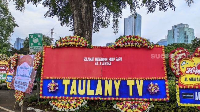 Karangan bunga nyeleneh kiriman Andre Taulany di lokasi ngunduh mantu Al Ghazali di Jakarta Convention Center, Senayan, Kamis, 19 Juni 2025. [Suara.com/Adiyoga Priyambodo]