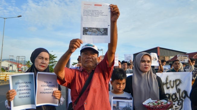 Keluarga Afif Maulana, pelajar SMP yang tewas diduga akibat penyiksaan oleh polisi tahun lalu, membawa poster di Tempat Kejadian Perkara saat aksi memperingati Hari Anti Penyiksaan sedunia di Jembatan Kuranji, Padang, Sumatera Barat, Selasa (24/6/2025). [ANTARA FOTO/Iggoy el Fitra/bar]