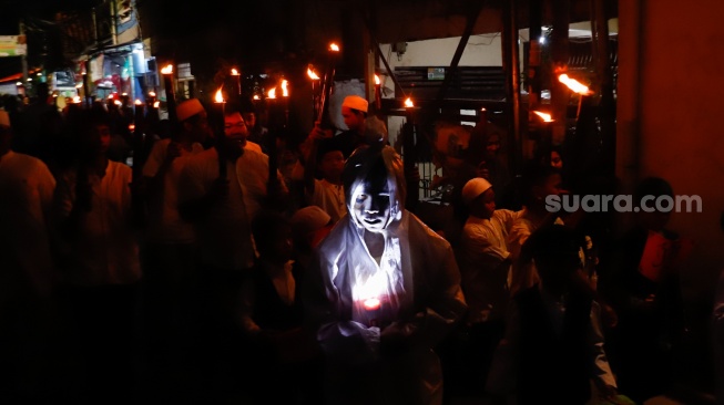 Sejumlah warga mengikuti pawai obor di RW 08 Kelurahan Menteng, Jakarta, Kamis (26/6/2025). [Suara.com/Alfian Winanto]