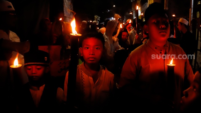 Sejumlah warga mengikuti pawai obor di RW 08 Kelurahan Menteng, Jakarta, Kamis (26/6/2025). [Suara.com/Alfian Winanto]