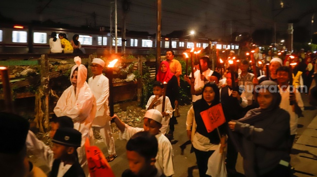 Sejumlah warga mengikuti pawai obor di RW 08 Kelurahan Menteng, Jakarta, Kamis (26/6/2025). [Suara.com/Alfian Winanto]