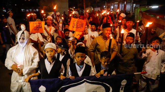 Sejumlah warga mengikuti pawai obor di RW 08 Kelurahan Menteng, Jakarta, Kamis (26/6/2025). [Suara.com/Alfian Winanto]