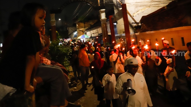 Sejumlah warga mengikuti pawai obor di RW 08 Kelurahan Menteng, Jakarta, Kamis (26/6/2025). [Suara.com/Alfian Winanto]