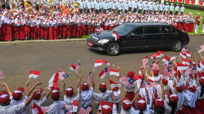 Sejumlah siswa SD menyambut kedatangan mobil yang membawa Presiden Prabowo Subianto dan Perdana Menteri Malaysia Anwar Ibrahim di Istana Merdeka, Jakarta, Jumat (27/6/2025). [ANTARA FOTO/Hafidz Mubarak A/app/nym.]
